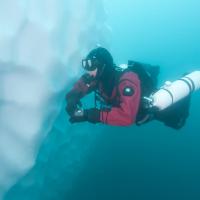 Plongeur longeant la paroi d'un iceberg dans le fjord Sermilik. La profondeur moyenne est d'environ 800 m. Côte est du Groenland